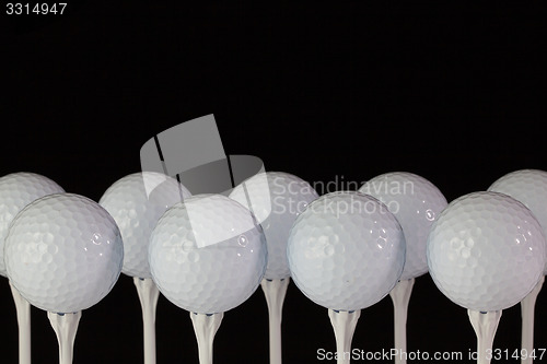 Image of White golf balls on a white tees