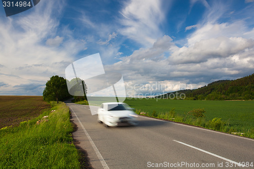 Image of Empty road between summer field at sunset