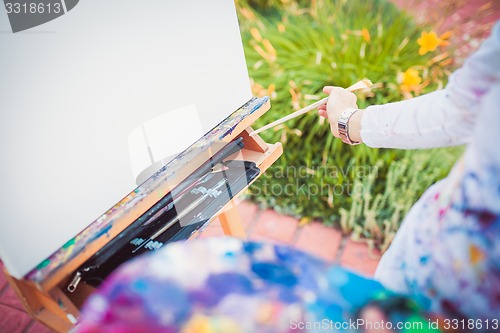 Image of Hand with paintbrush and easel