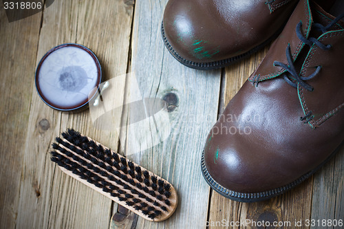 Image of brown boots, shoe polish and shoe brush