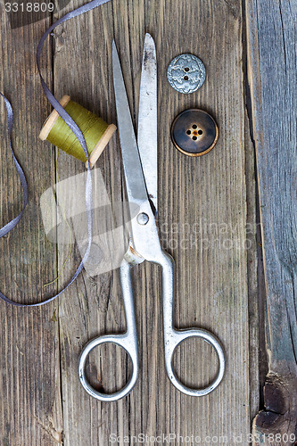 Image of vintage dressmaker scissors, bobbin of thread and buttons