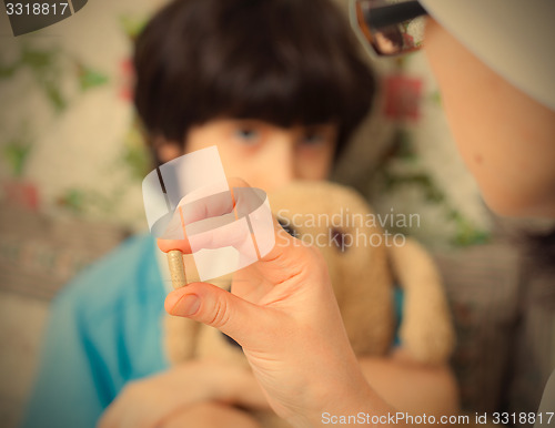 Image of hand of a doctor with pill and boy