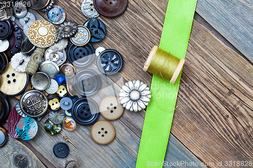 Image of vintage buttons, spool with thread and green tape