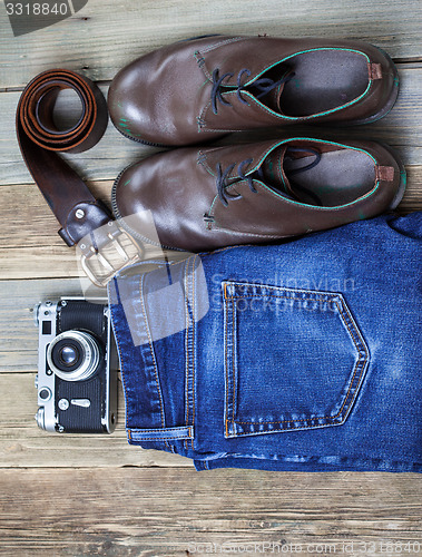 Image of Still life with blue jeans, brown boots, leather belt and camera