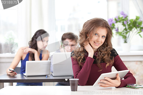 Image of smiling young girl with tablet in classroom