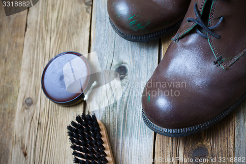 Image of brown boots, shoe polish and shoe brush