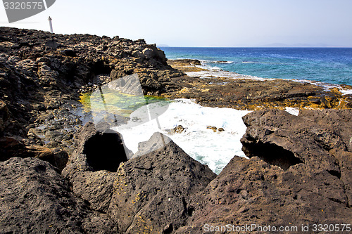 Image of hervideros brown rock in white coast lighthouse