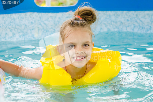 Image of Cheerful girl swimming in pool swimming vest
