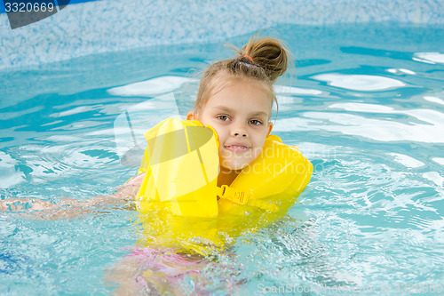 Image of Girl swimming in the pool in the lifejacket