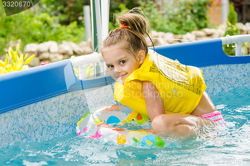 Image of Cheerful girl bathing trying to get into the swimming circle