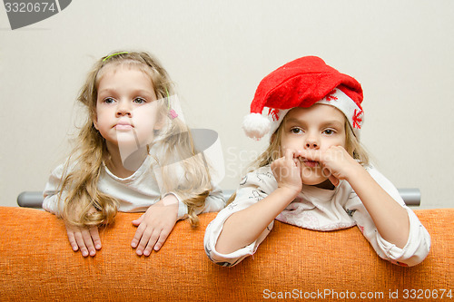 Image of Two girls looking to left leaning back on the couch