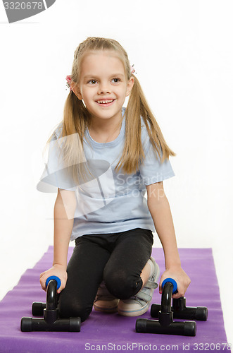 Image of Six year old girl on a rug with stops for push-ups