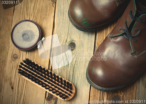 Image of brown boots, shoe polish and shoe brush