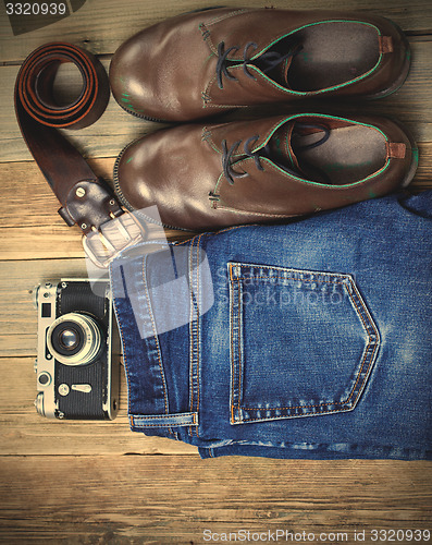 Image of Still life with blue jeans, brown boots, leather belt and camera