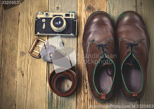 Image of sturdy boots, leather belt, and rangefinder camera