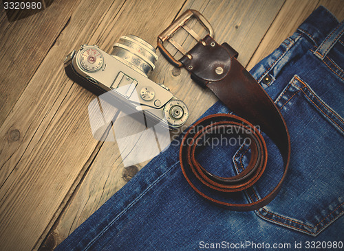 Image of rangefinder camera, vintage leather belt and blue jeans