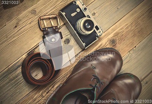 Image of sturdy brown boots, leather belt, and rangefinder camera