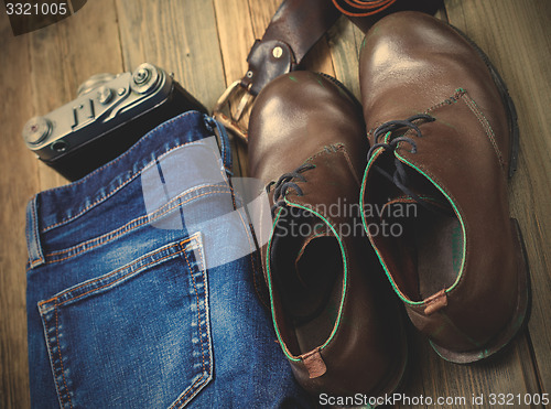 Image of blue jeans, brown boots, leather belt and rangefinder camera