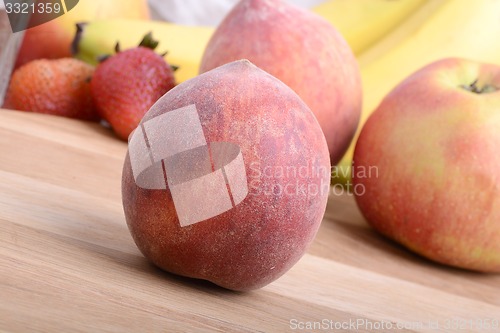 Image of peach,  apple and strawberry on wooden plate 