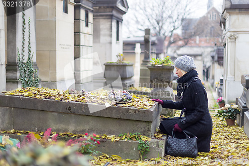 Image of Solitary woman visiting relatives grave.