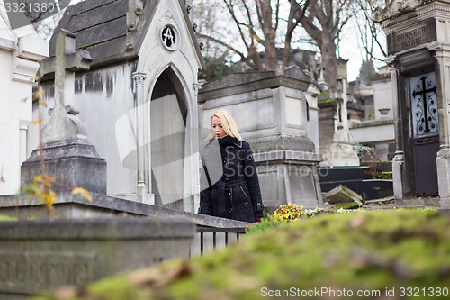 Image of Solitary woman visiting relatives grave.