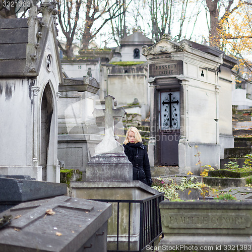 Image of Solitary woman visiting relatives grave.