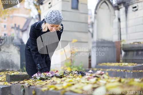 Image of Solitary woman visiting relatives grave.