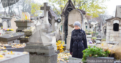 Image of Solitary woman visiting relatives grave.