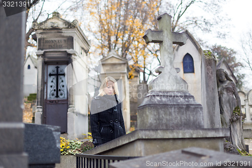 Image of Solitary woman visiting relatives grave.