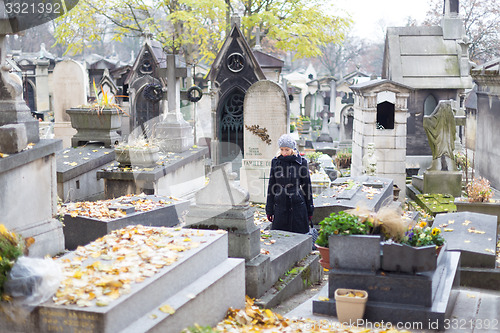 Image of Solitary woman visiting relatives grave.