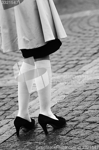 Image of female legs in socks and black shoes 