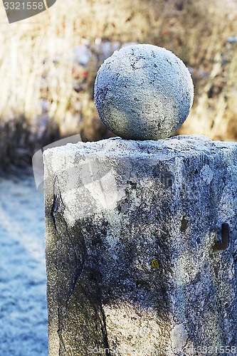 Image of granite ball on a pedestal covered with frost