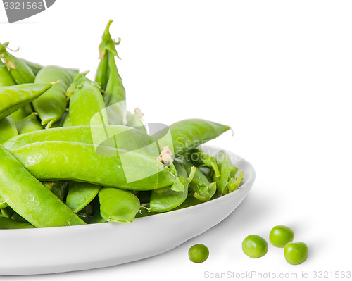 Image of Closeup pile of green peas in pods in white plate