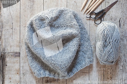 Image of wool grey hat, knitting needles and yarn