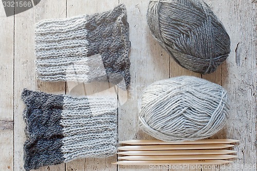 Image of wool grey legwarmers, knitting needles and yarn