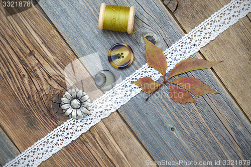 Image of still life with lace tape, vintage buttons, spools of thread and