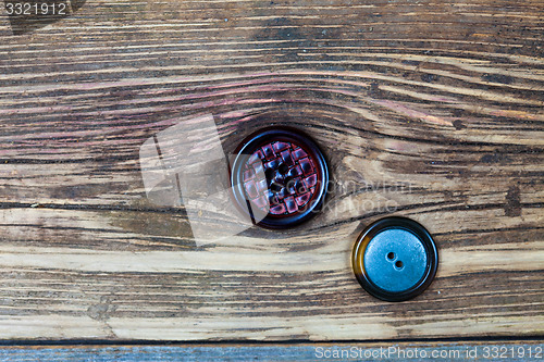 Image of two vintage buttons on aged wood surface