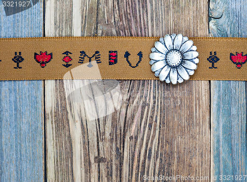 Image of vintage band with embroidered ornaments and old button flower