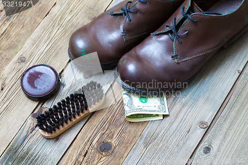 Image of boots, brush, shoe polish and dollar