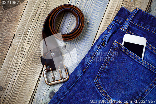 Image of old blue jeans, vintage leather belt and smartphone