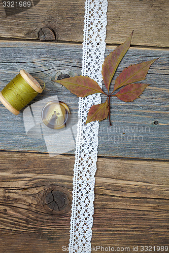 Image of still life with lace ribbon, vintage buttons, spools of thread a