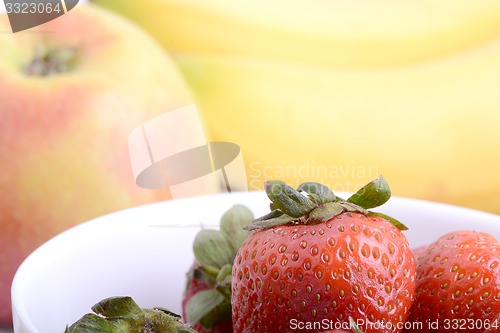 Image of Fruits. Arrangement of various fresh ripe fruits: bananas, apple and strawberries closeup