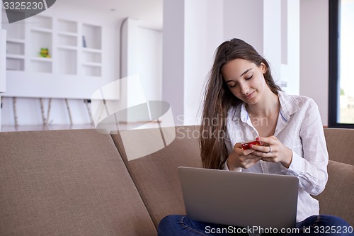 Image of relaxed young woman at home working on laptop computer