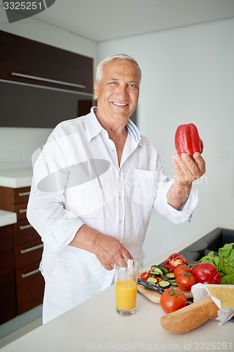 Image of man cooking at home preparing salad in kitchen