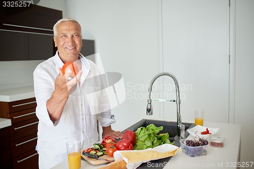 Image of man cooking at home preparing salad in kitchen