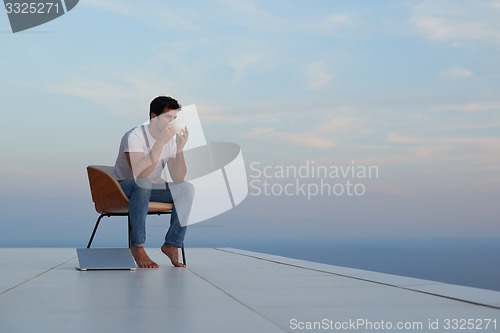 Image of relaxed young man at home on balcony