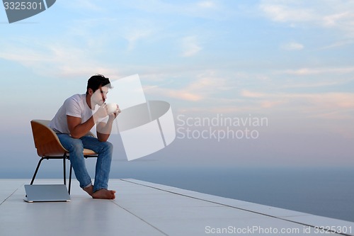 Image of relaxed young man at home on balcony