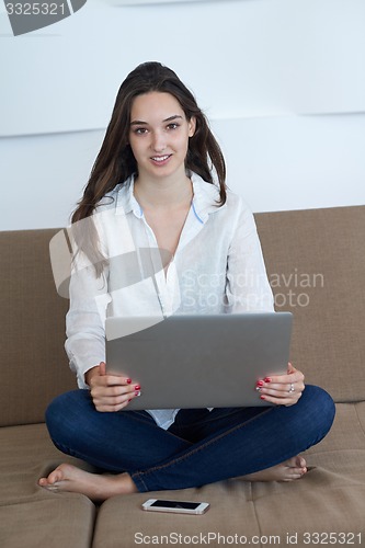 Image of relaxed young woman at home working on laptop computer