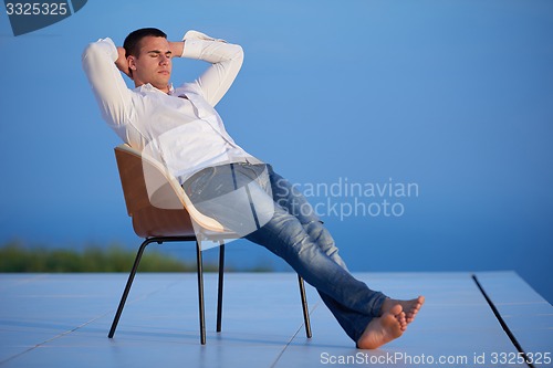 Image of relaxed young man at home on balcony