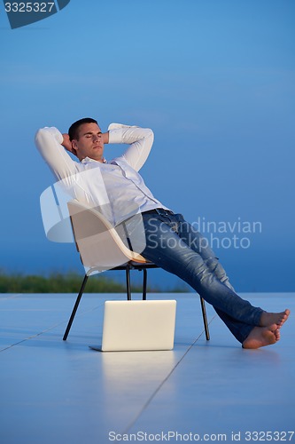 Image of relaxed young man at home on balcony